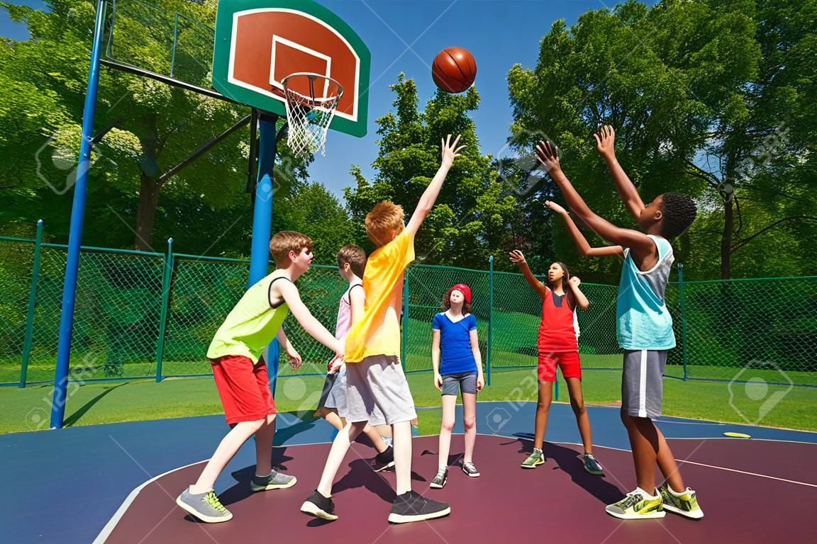 Jugendliche spielen Basketball-Spiel zusammen auf dem Spielplatz im sonnigen Sommertag