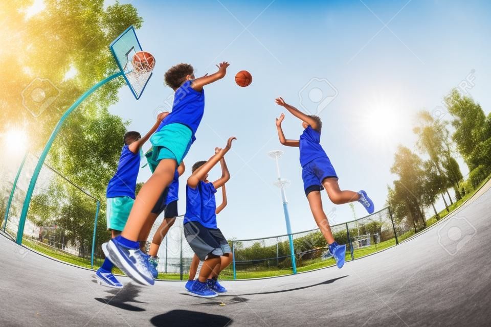 Fisheye view of teenagers playing basketball game together on the playground during sunny summer day