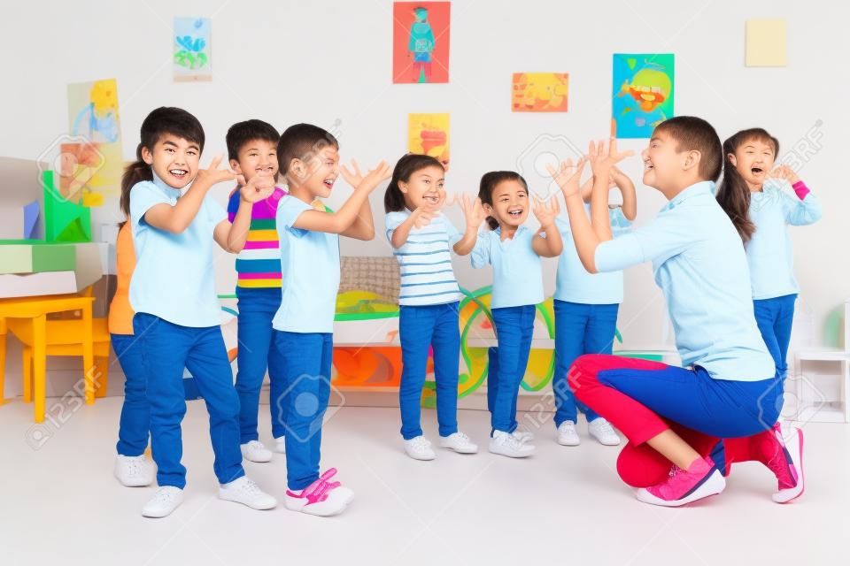 Группа детей мальчиков и девочек повторяющимися жест руками, играя удовольствие от игры