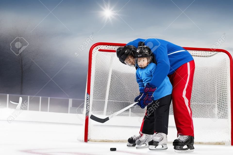 アイス ホッケーを再生すると氷の上ゲート近くに立っているアイス ホッケー用スティックを押したまま息子を教える親父