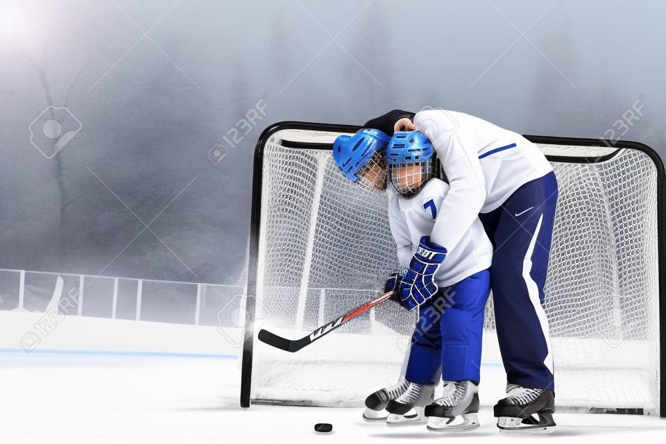 Vater lehrt Sohn, Eishockey zu spielen und Hockeyschläger stehen in der Nähe von Gates auf Eis