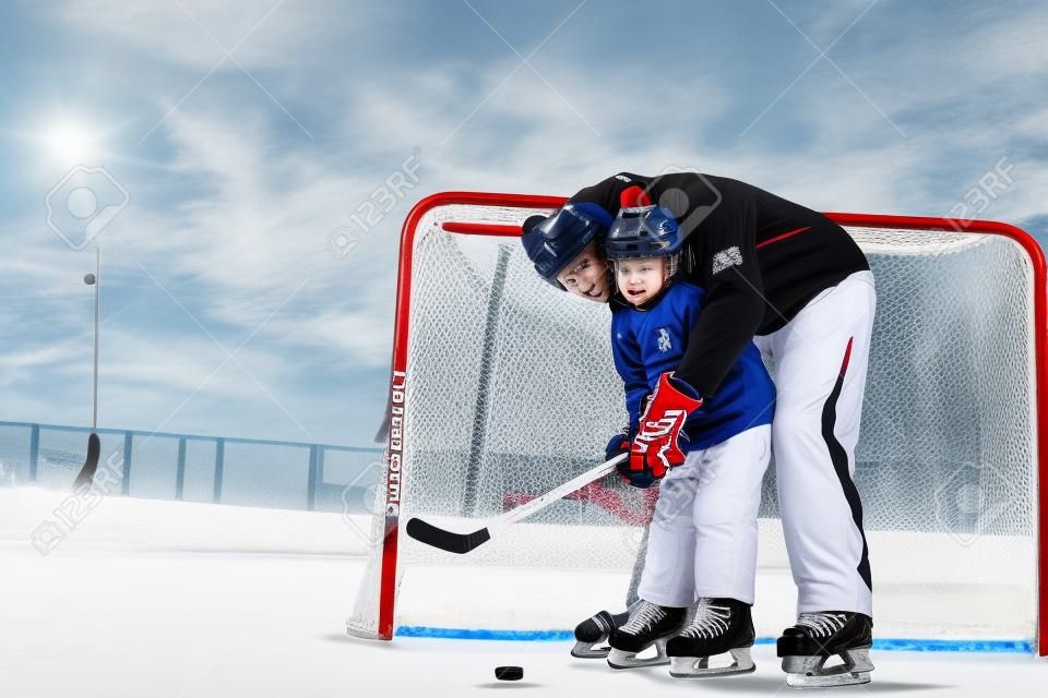 Vater lehrt Sohn, Eishockey zu spielen und Hockeyschläger stehen in der Nähe von Gates auf Eis