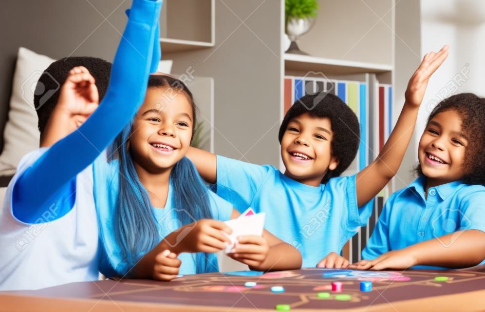 Mutlu çocuklar, kovanı beş vererek oyun masada oturan ve oda iskambil
