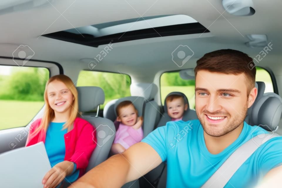 Portrait of young father driving his family in the car