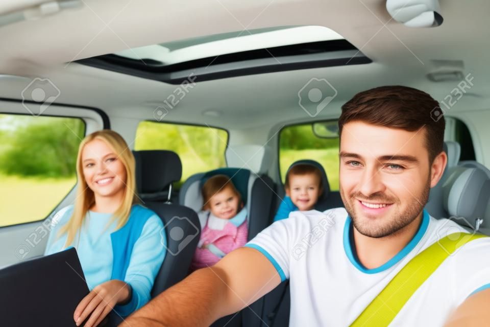 Portrait of young father driving his family in the car