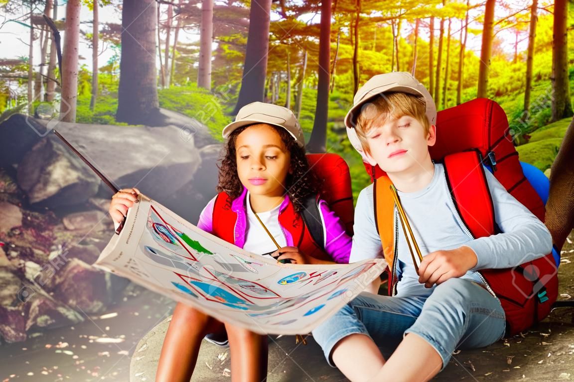 Dos niños en el bosque navegan con mapa de búsqueda del tesoro.