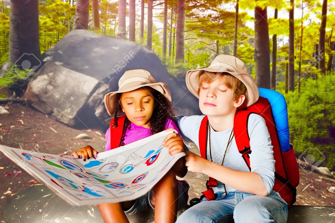 森の中の2人の子供が地図の宝探しでナビゲート