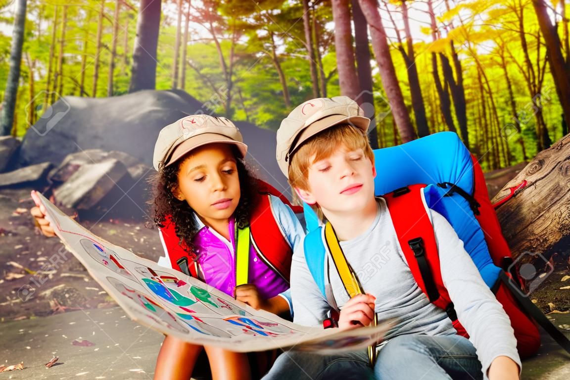 Dos niños en el bosque navegan con mapa de búsqueda del tesoro.