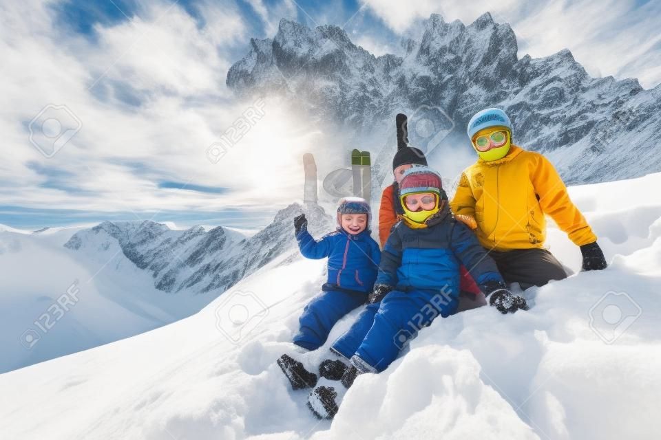 Lustiges Gruppenporträt von Kindern sitzt zusammen im Schnee über herrlichen Berggipfeln in den Alpen