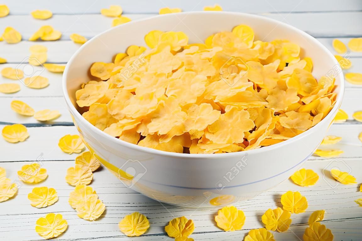 White bowl of corn flakes on a wooden surface