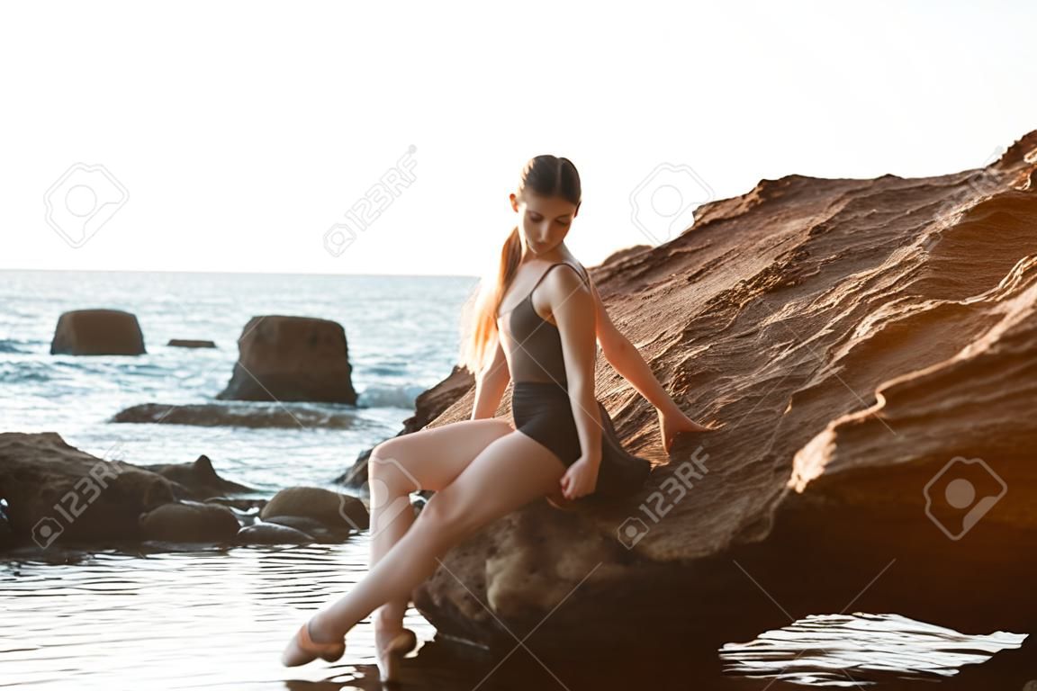 Dança bonita da bailarina, levantando na rocha na praia, fundo do mar.