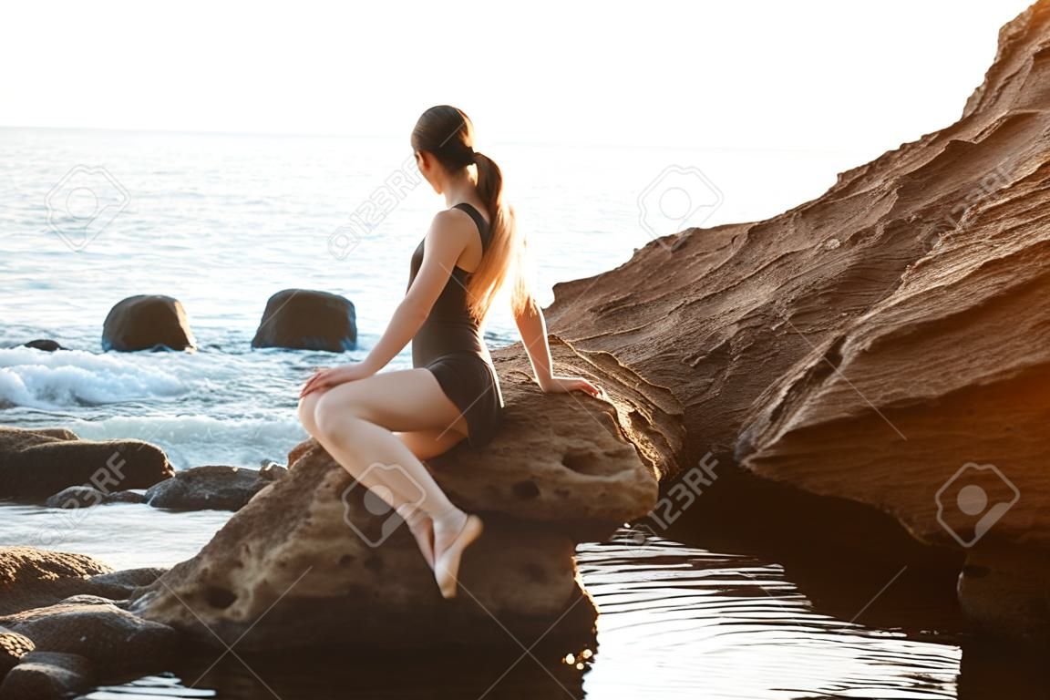 Bello dancing della ballerina, posante su roccia alla spiaggia, fondo del mare.