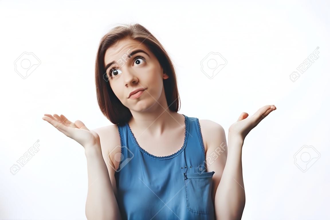 Не знаю, извини. Привлекательная смешная темноволосая кавказская девушка в повседневной одежде смотрит в сторону с неловким выражением лица, разводя руками. Женщина делает вид, что ничего не знает о чужой мужской футболке в доме.