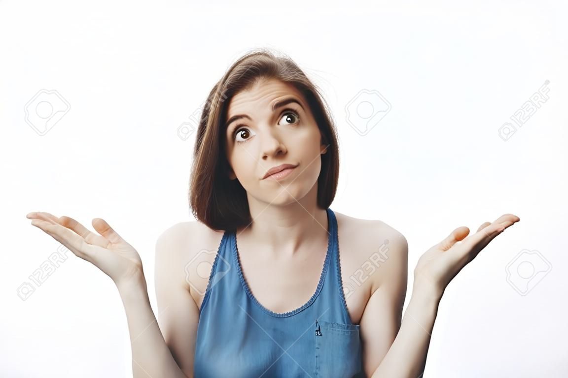 Не знаю, извини. Привлекательная смешная темноволосая кавказская девушка в повседневной одежде смотрит в сторону с неловким выражением лица, разводя руками. Женщина делает вид, что ничего не знает о чужой мужской футболке в доме.