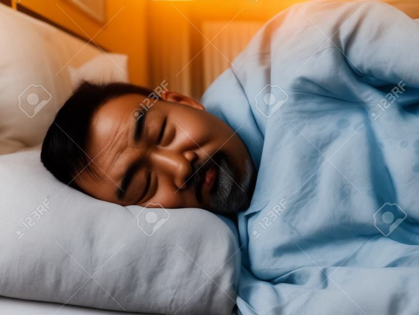 Homem asiático que dorme na luz da manhã com cara engraçada.