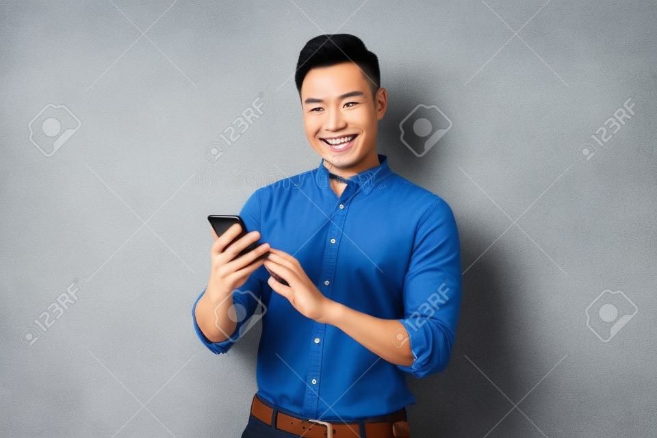 Il sorriso felice del volto di un bell'uomo asiatico usa lo smartphone.