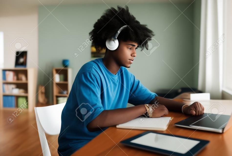 Widok z boku portret afroamerykańskiego nastolatka studiującego w domu lub w akademiku i korzystającego z laptopa, miejsce na kopię