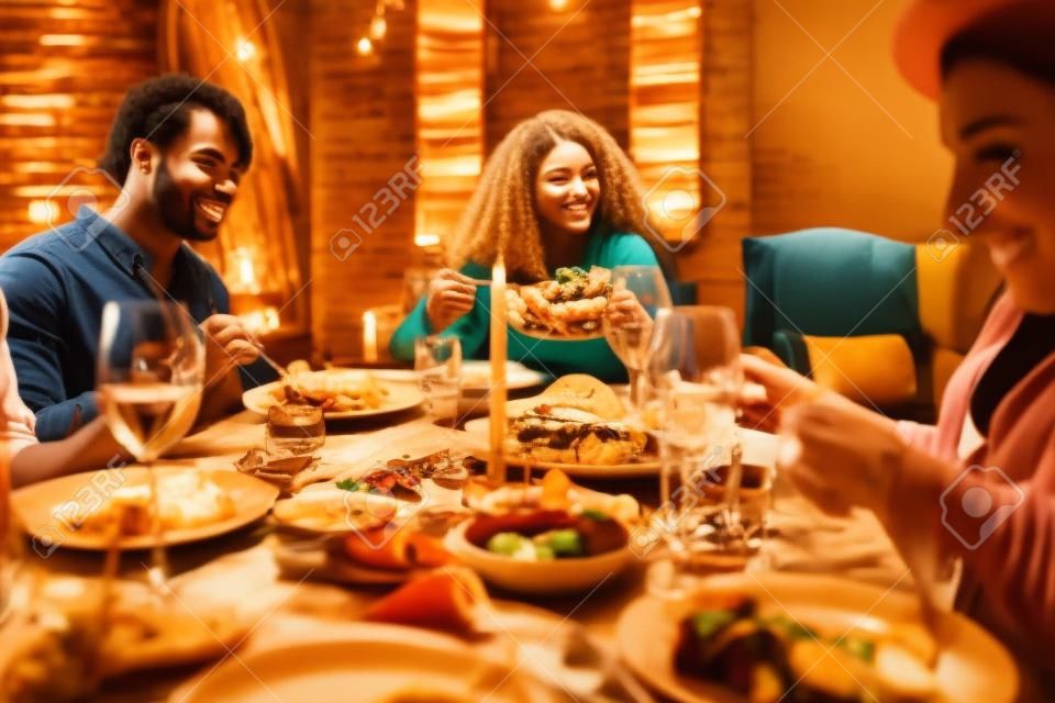 Retrato en tonos cálidos de diversos jóvenes disfrutando de una cena en la mesa en un ambiente acogedor