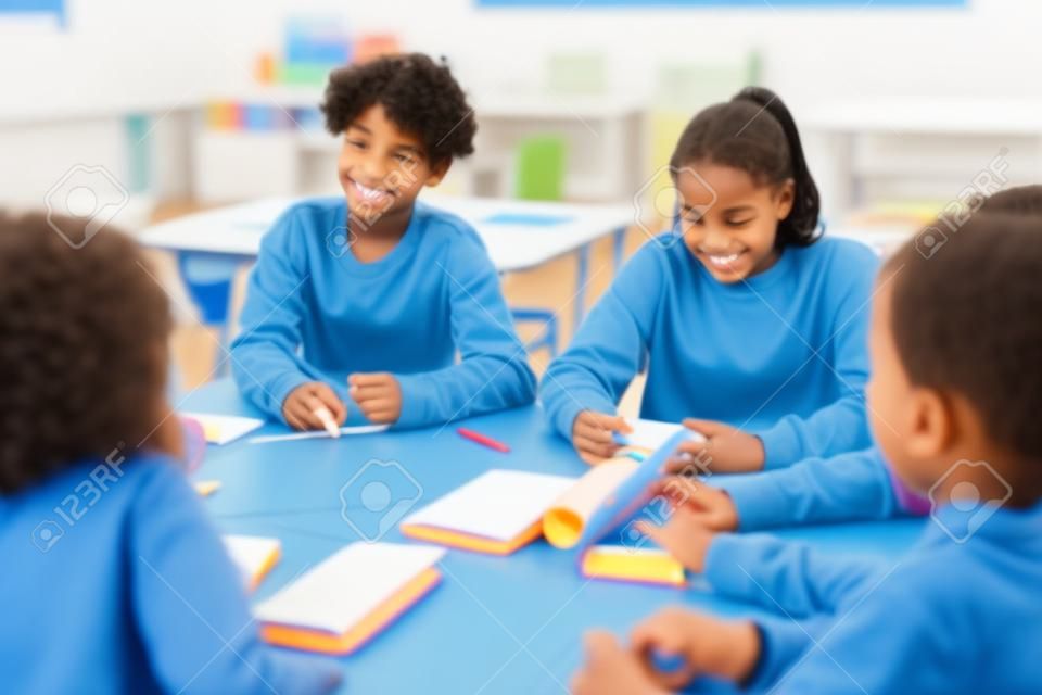 Verschiedene Kinder in Gruppenaktivitäten im Schulklassenzimmer mit Fokus auf lächelnden Jungen mit lockigem Haar