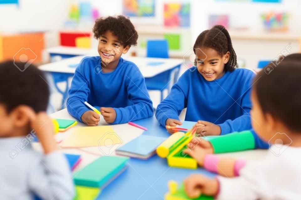Diverse kinderen in groep activiteit in school klaslokaal met focus op lachende jongen met krullend haar