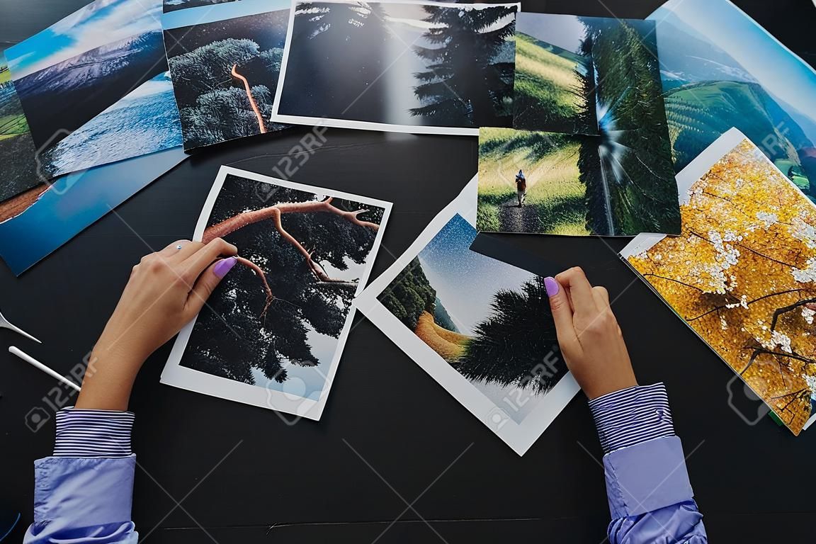 Hands of female photographer checking photos of landcapes she printed