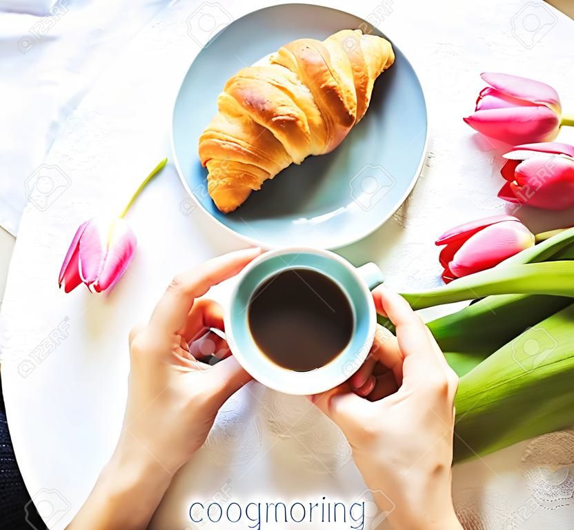 Girl with croissants and coffee, a bouquet of pink tulips, happy morning.