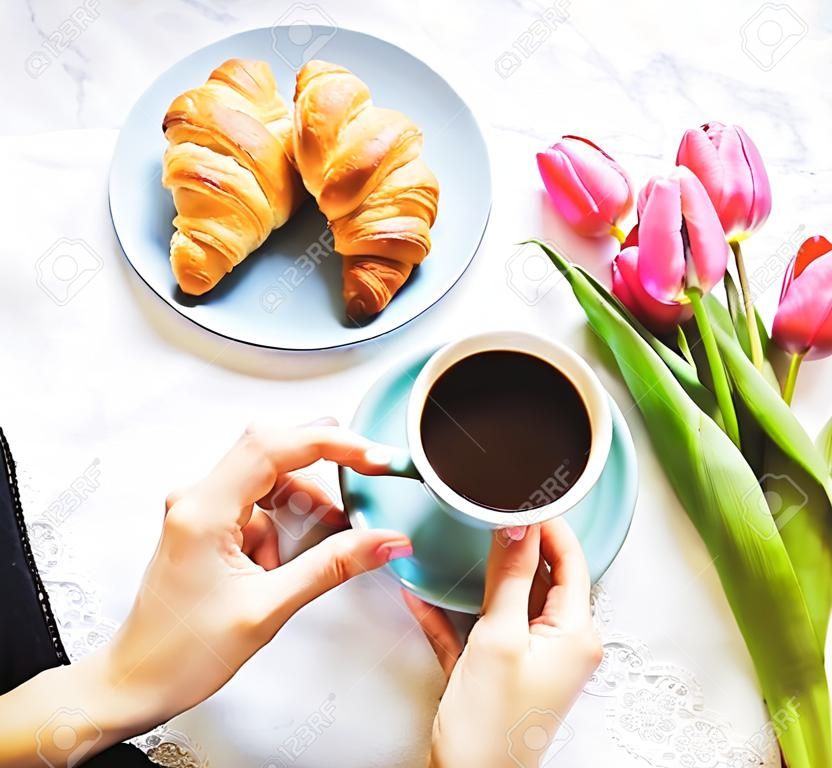 Girl with croissants and coffee, a bouquet of pink tulips, happy morning.