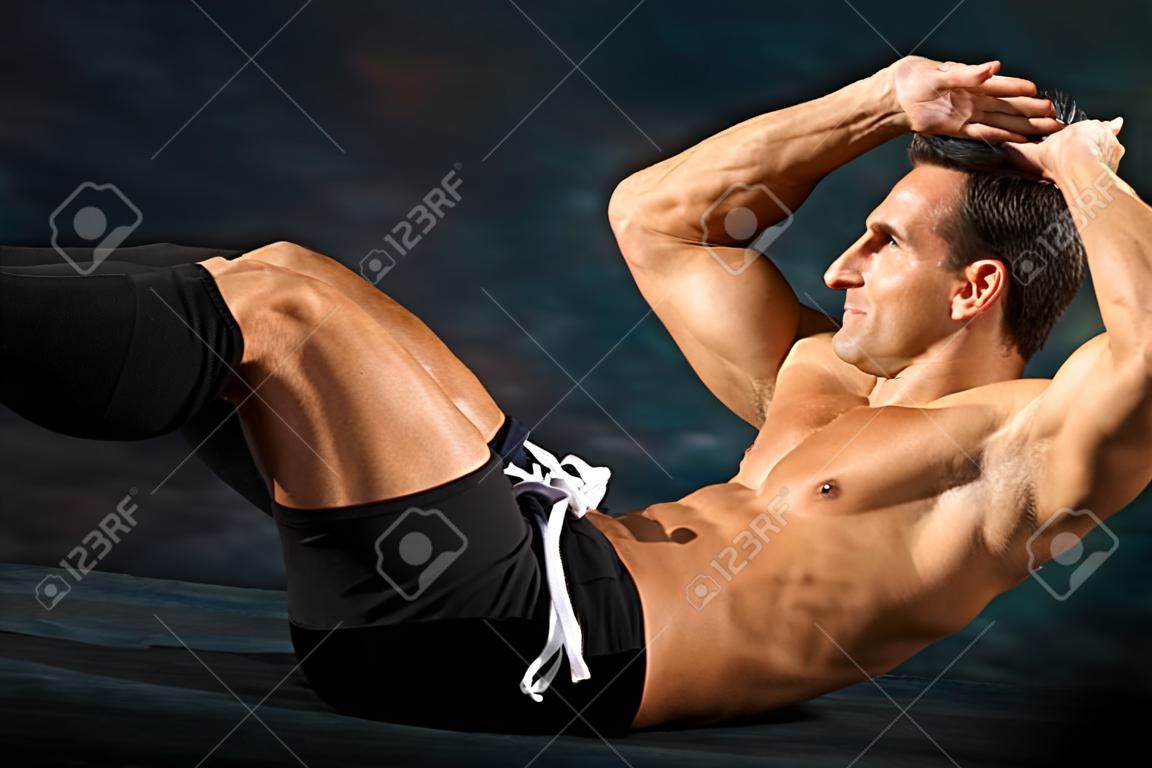 Hombre atlético realiza ejercicios de calistenia situp para el fortalecimiento abdominal.