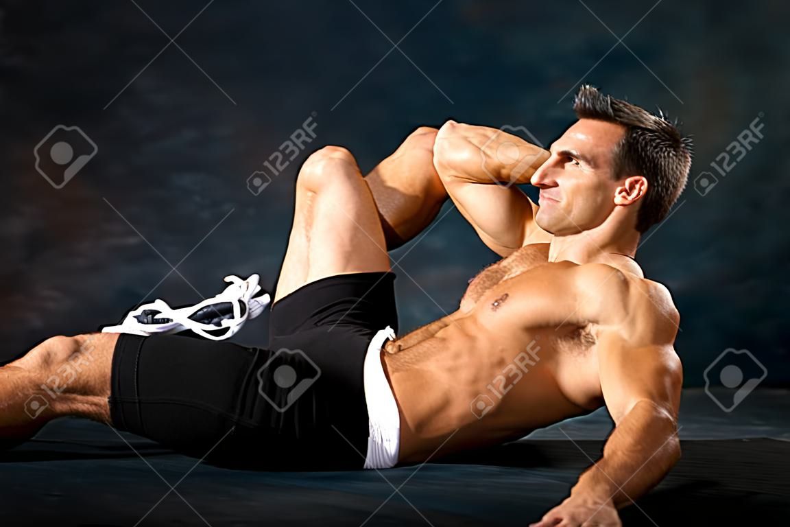 Hombre atlético realiza ejercicios de calistenia situp para el fortalecimiento abdominal.