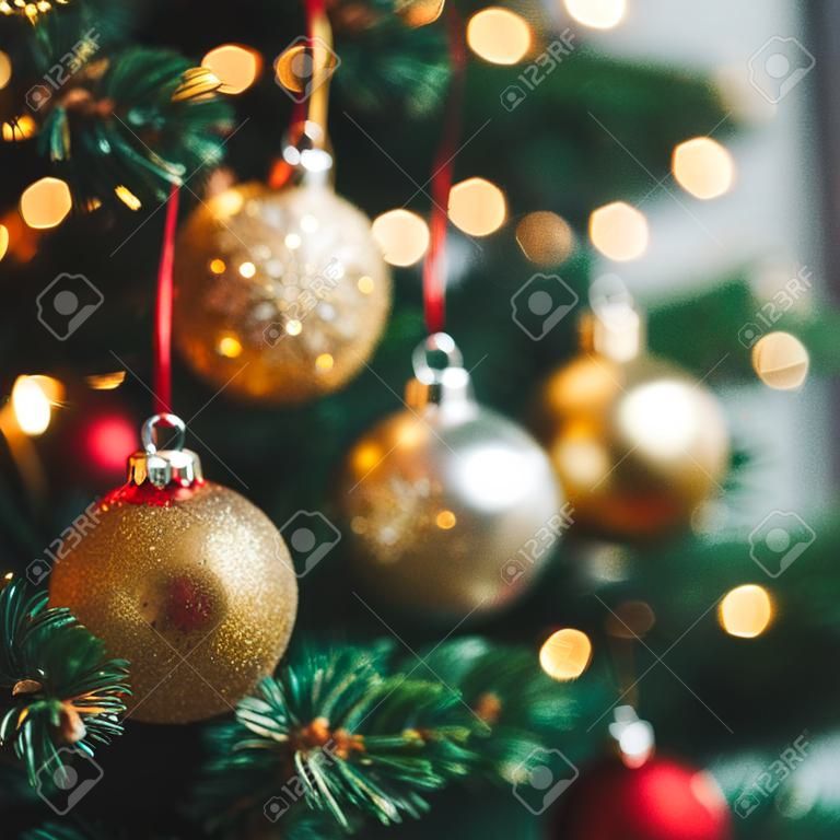 Nahaufnahme von roten und goldenen Weihnachtsbaumornamenten vor einem defokussierten Lichthintergrund