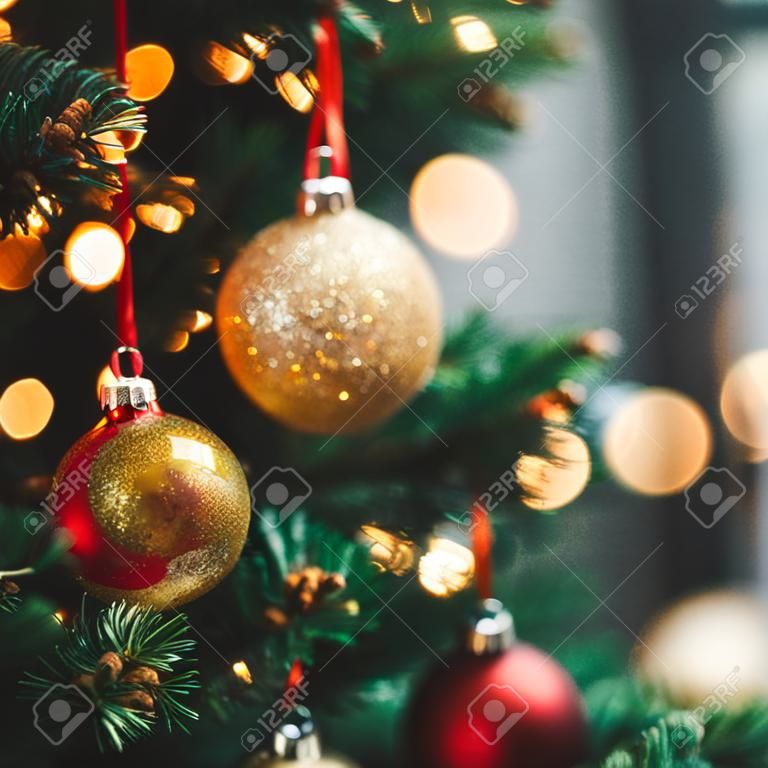 Nahaufnahme von roten und goldenen Weihnachtsbaumornamenten vor einem defokussierten Lichthintergrund