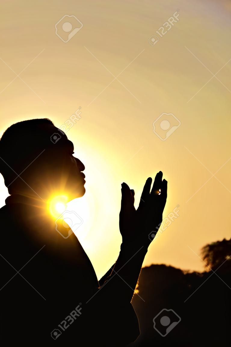Silhueta de um muçulmano orando sobre o pôr do sol dourado
