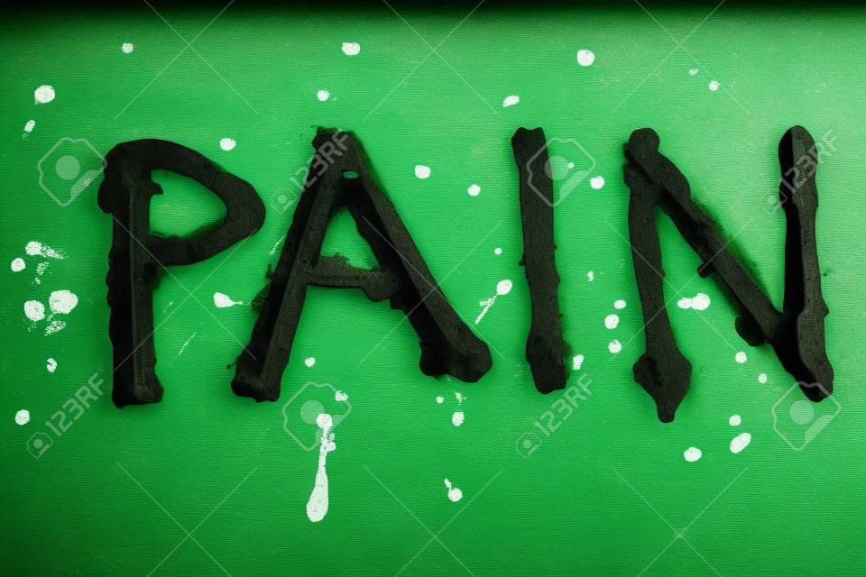 Le mot douleur peint par de la peinture verte sur une vieille table en métal