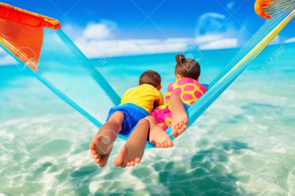 Hermano y hermana cabritos que se relajan en hamaca en la playa tropical