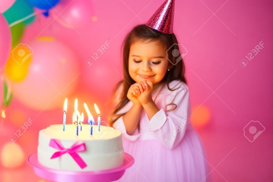 cute little child girl blowing candles on birthday cake and celebrating birthday