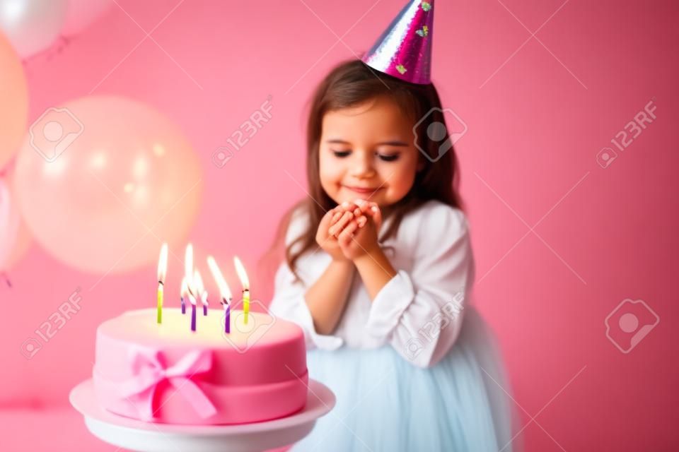 cute little child girl blowing candles on birthday cake and celebrating birthday