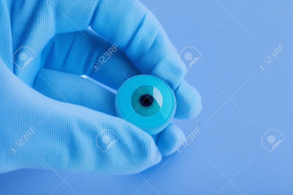 Ophthalmologist or surgeon holds in hand dressed in a blue glove eye (eyeball). Concept photo for ocular prosthesis, diagnosis and treatment of ophtalmic diseases, surgical operations on eyes