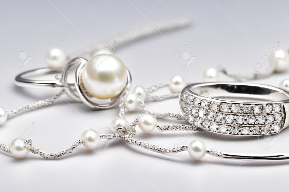 Silber Ring mit Edelsteinen und Perlen sind zusammen mit einer silbernen Kette auf Acryl
