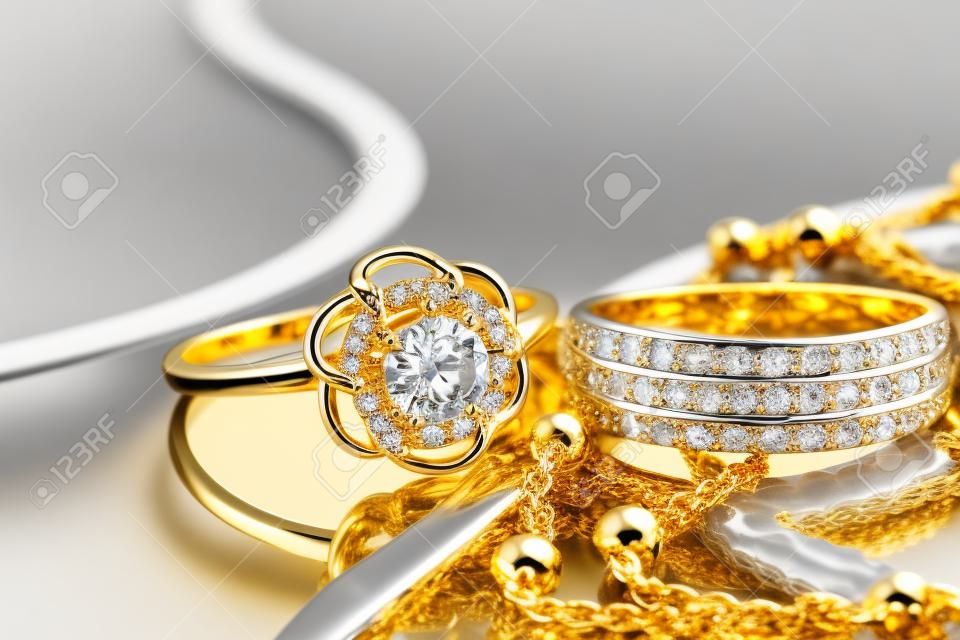 Gouden, zilveren ringen en kettingen van verschillende stijlen liggen samen op het reflecterende oppervlak