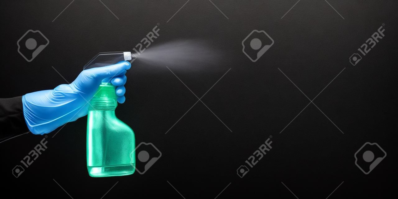 手帶橡膠手套拿著一瓶清洗和噴塗液體，在黑色的背景