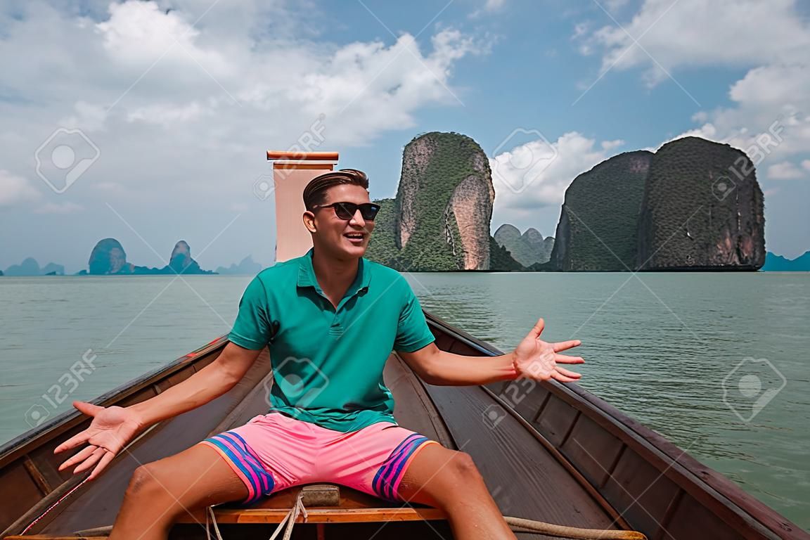 Vacation in sunny Asia. Man on a tour of the islands of Thailand. Activities and adventures. The male floats on a national Thai boat Longtail.