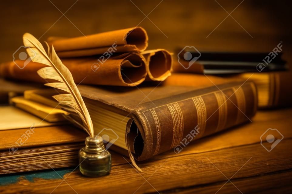 Quill pen y una hoja de papiro enrollada sobre una mesa de madera con libros antiguos