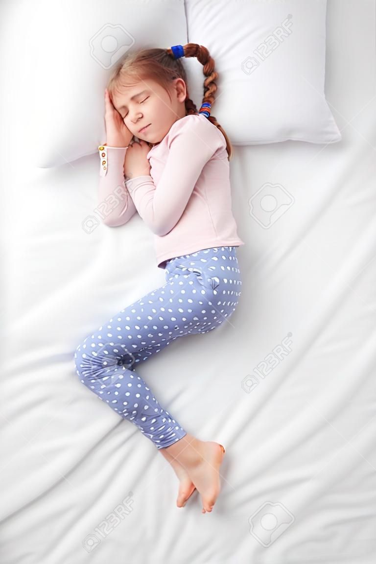 上面白いベッドで寝ているおさげのかわいい少女の写真。寝ているポーズの概念