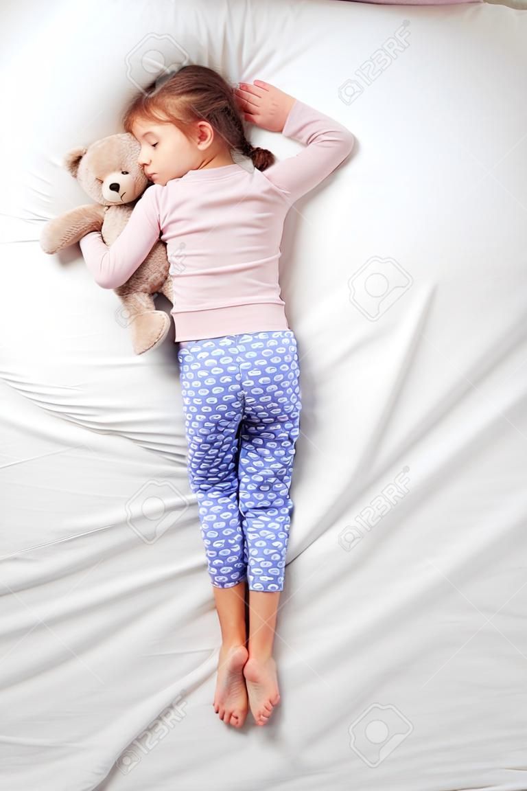 Draufsicht Foto des kleinen netten Mädchens Schlafen auf dem Bauch mit Teddybär. Konzept der schlafenden Posen
