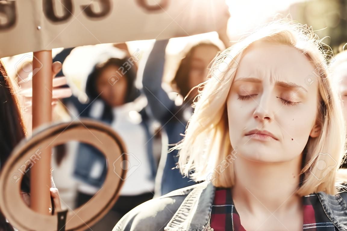 Confie Nas Mulheres. Close Up Foto De Jovem Loira Está Chorando Enquanto Em  Pé Na Frente De Ativistas Do Sexo Feminino Na Estrada Durante A Marcha De  Protesto. Foto Royalty Free, Gravuras,