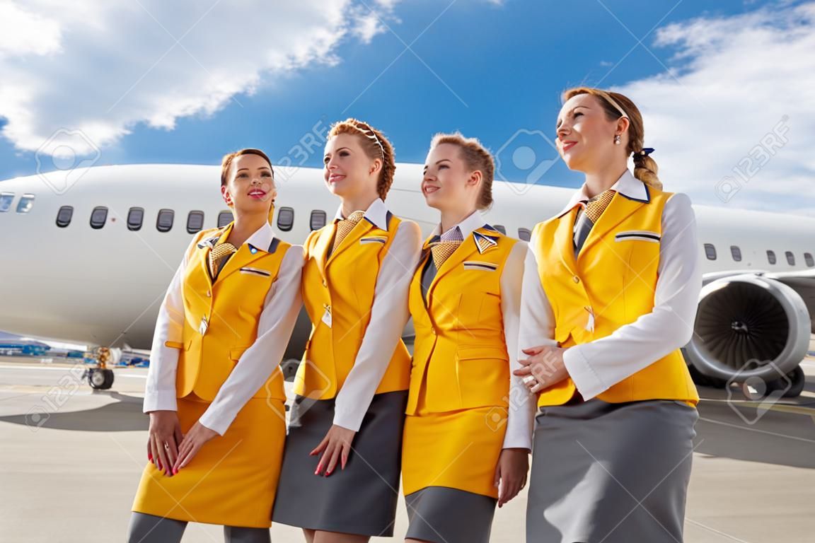 Vrolijke stewardessen in de buurt van vliegtuigen op het vliegveld