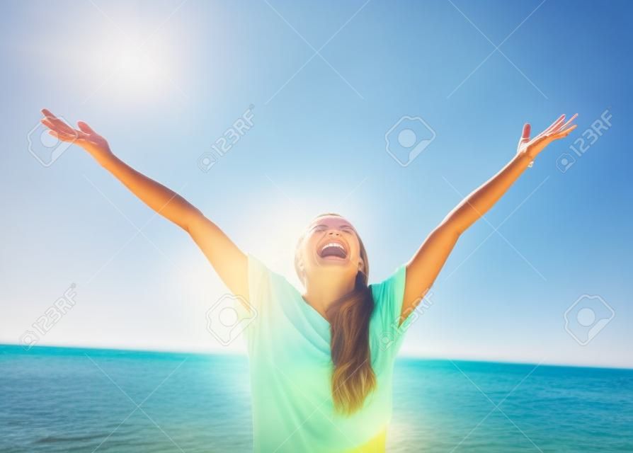Vrouw glimlachende armen omhoog naar de blauwe lucht, vieren vrijheid. Positieve menselijke emoties, gezicht uitdrukking gevoel leven perceptie succes, vrede van geest concept. Gratis Gelukkig meisje op het strand genieten van de natuur
