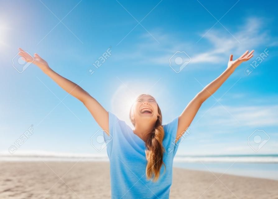 Женщина улыбается поднятыми руками до голубого неба, празднуя свободу. Положительные эмоции человека, выражением лица чувство восприятия жизни успеха, спокойствие концепции. Бесплатный Счастливый девушка на пляже, наслаждаясь природой
