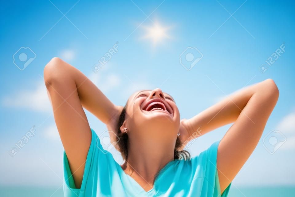 Sonriente mujer de los brazos levantados al cielo azul, celebración de la libertad. Emociones humanas positivas, expresión de la cara sintiéndose éxito percepción vida, la paz de la mente el concepto. Niña feliz gratuito en la playa disfrutando de la naturaleza