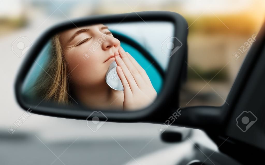 Rückspiegel Blick Reflexion schläfrig müde müde gähnend erschöpft junge Frau ihr Auto im Verkehr nach langen Stunden Fahrt. Transport Schlafentzug Unfall Konzept